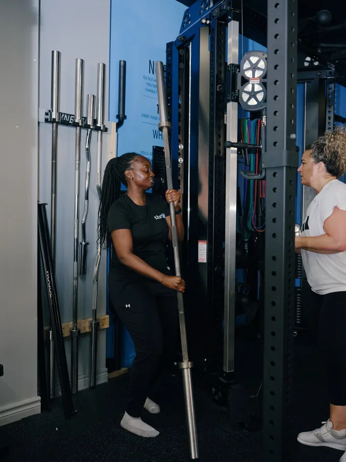 A coach and a member at the barbell rack at Thrive Fit in The Beaches