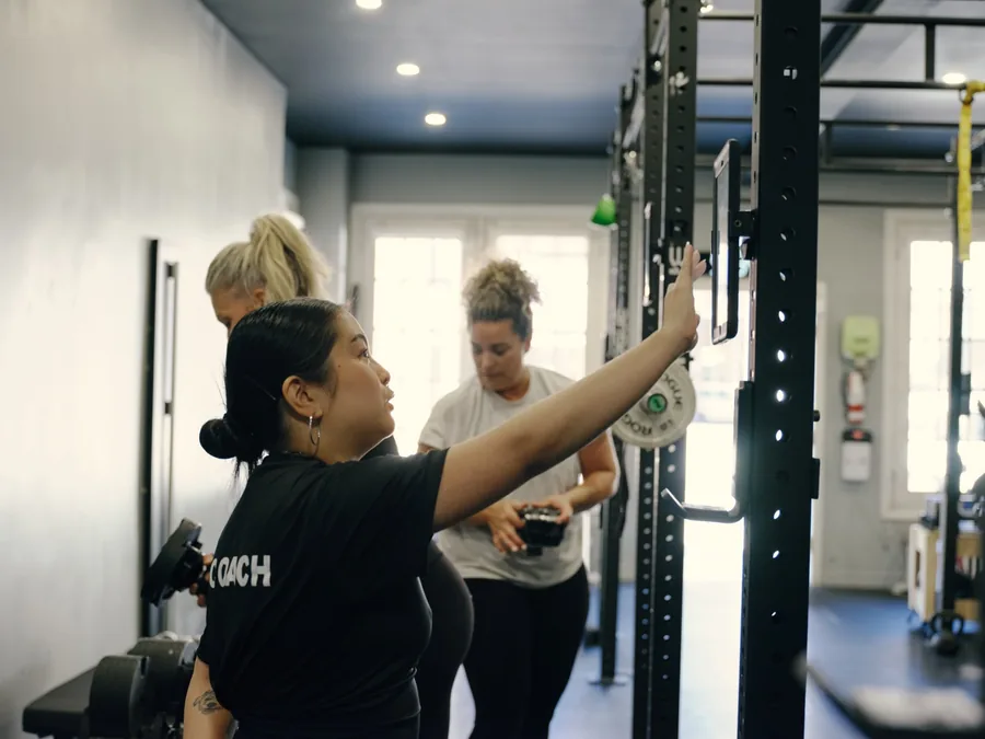 Thrive Fit: a coach setting up a rack for two members
