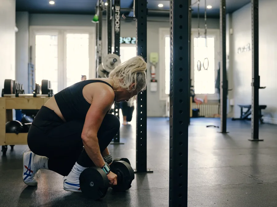 Thrive Fit: a member picking up a pair of dumbbells