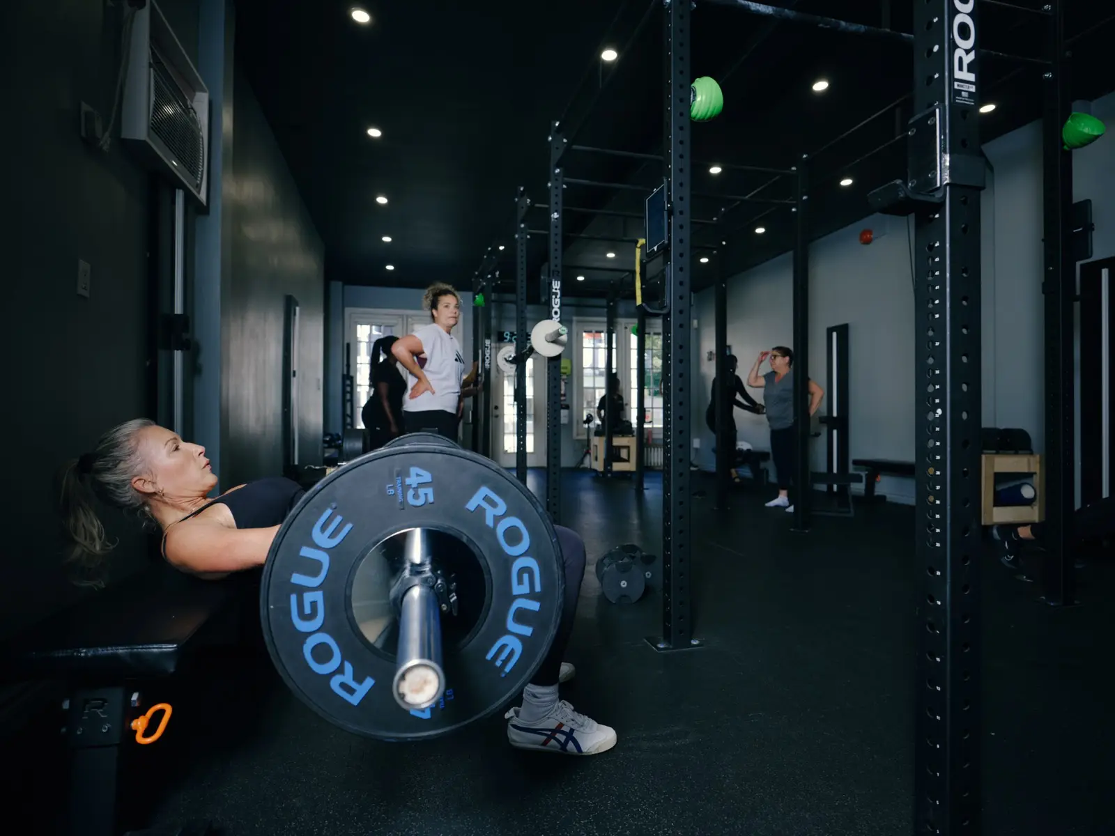 Thrive Fit: a member pressing a loaded barbell on the studio floor