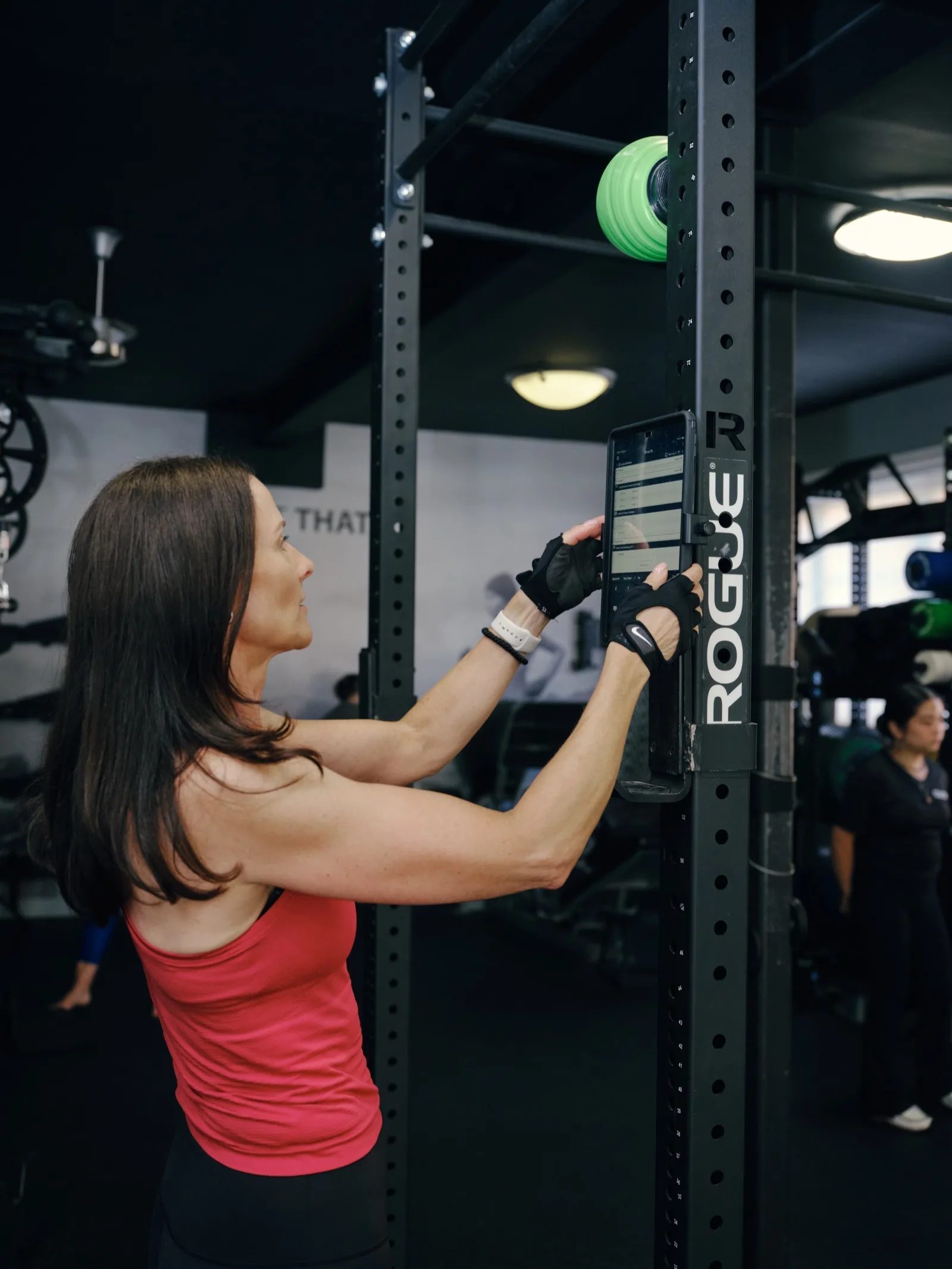A Thrive Fit member reading her own training programme from the tablet mounted on her rack